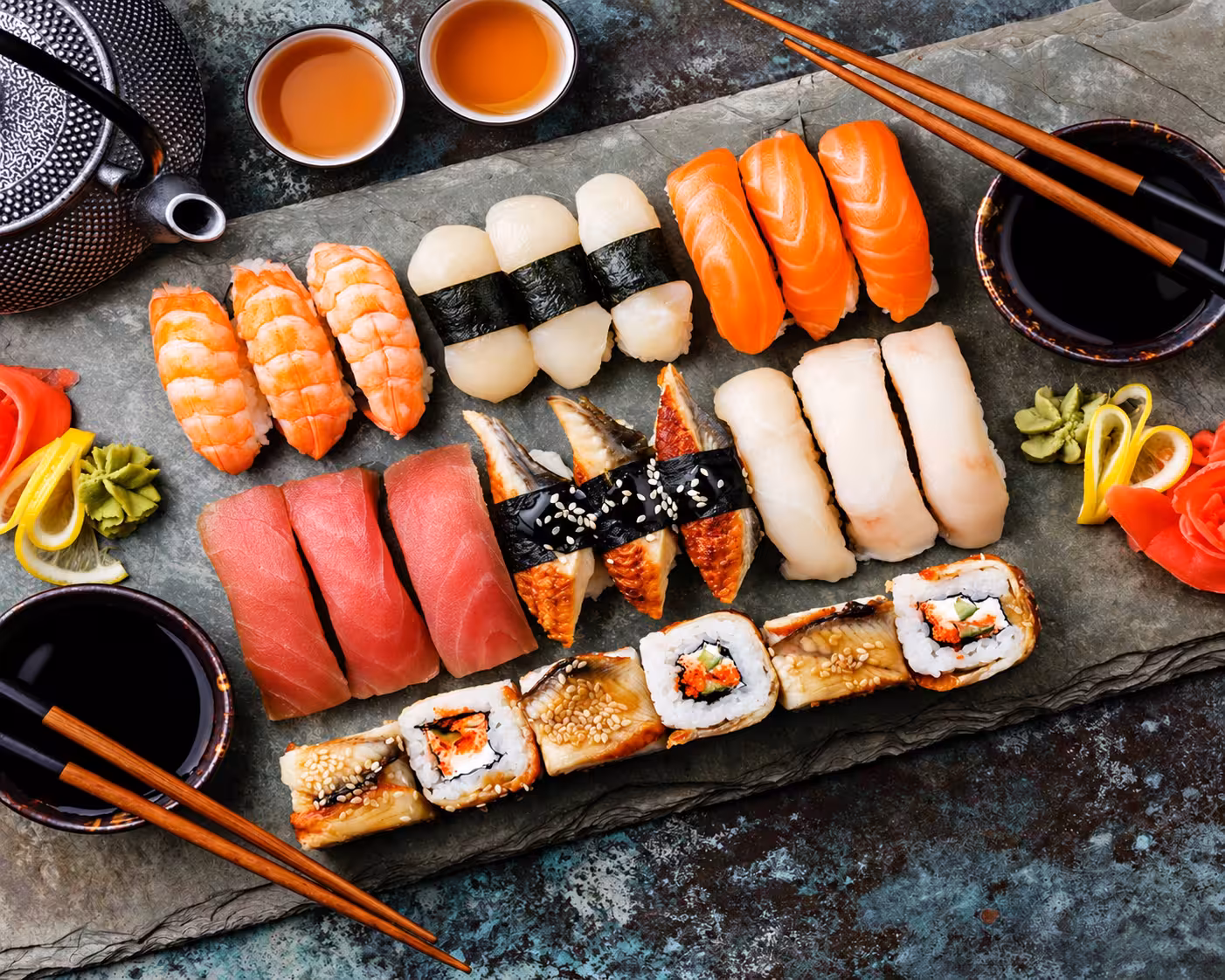 Assorted nigiri and sushi rolls arranged on a stone serving board